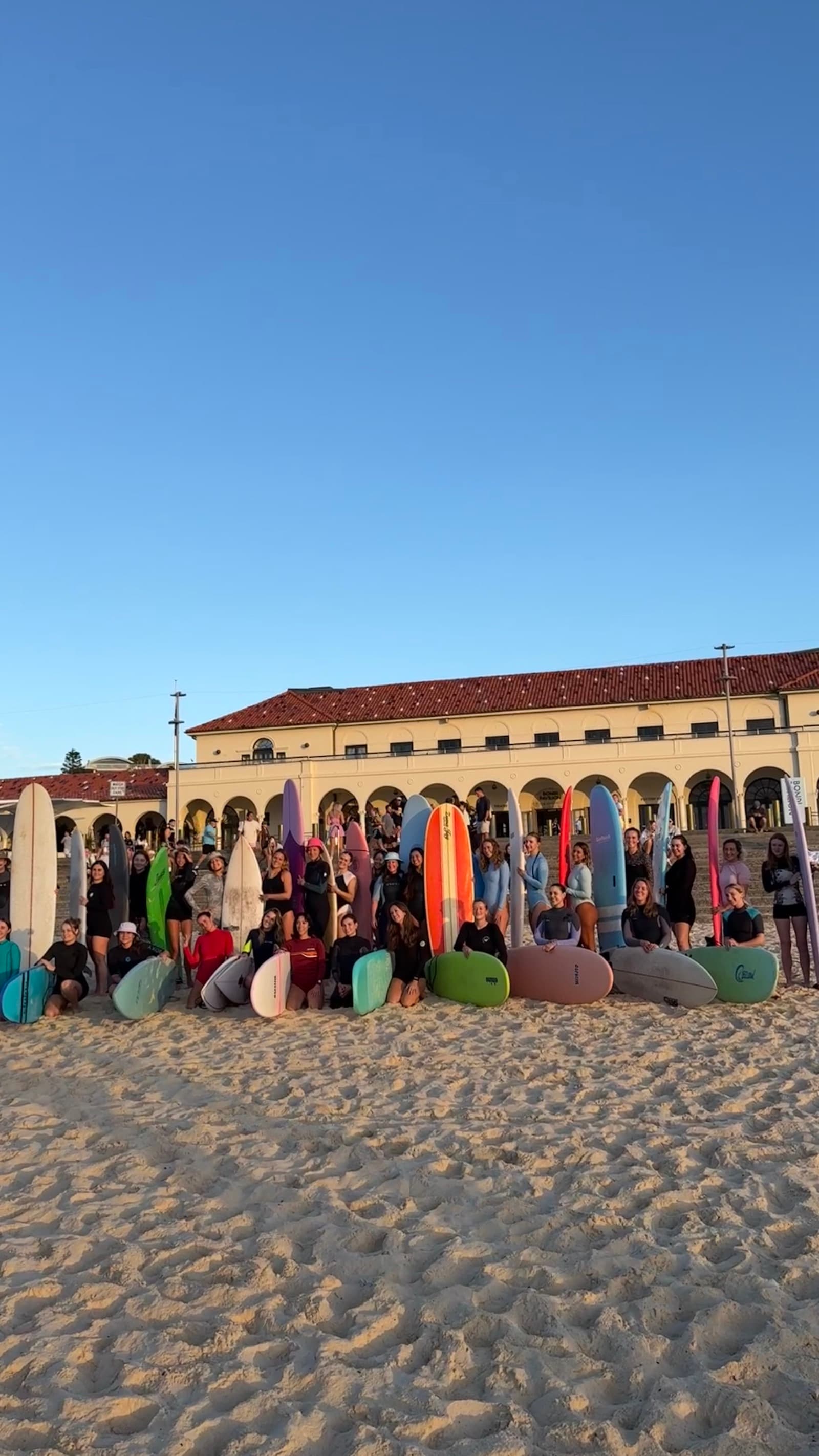 The Bondi Surf Sisters community with their boards on Bondi Beach